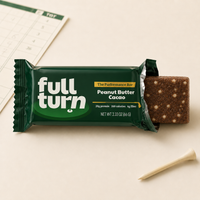 Full Turn Peanut Butter Cacao performance bar on a light surface with a ruler and cookie in the background.
